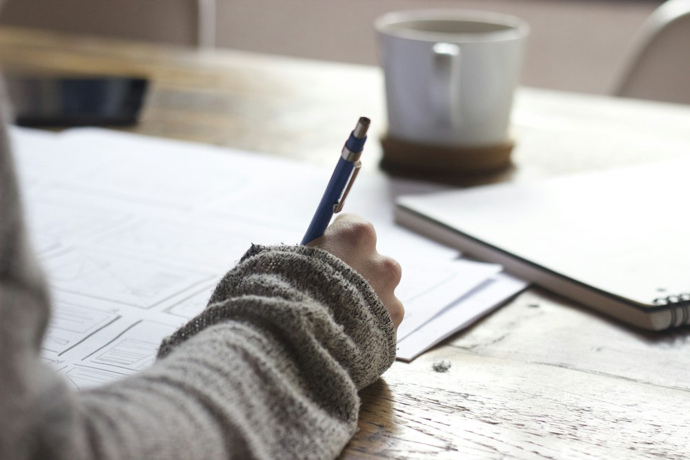 A learner making notes beside an open book